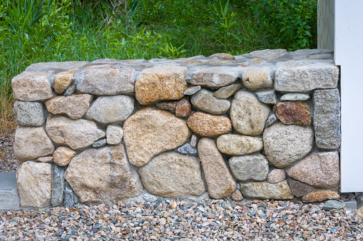 A newly constructed stone wall, artfully created using a variety of shapes, sizes, colors and textures of native stone.