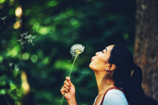 beautiful woman blowing on a dandelion