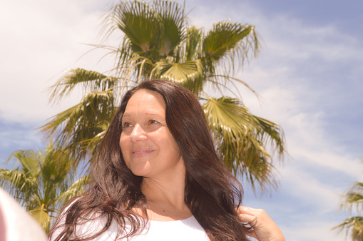 Portrait of a smiling woman standing in front of a palm tree