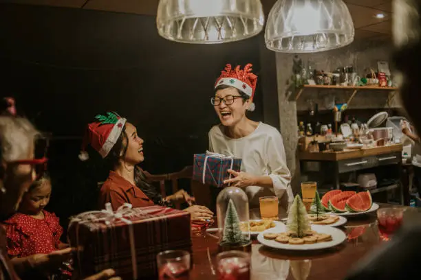 Photo of Merry Christmas and happy new year, Mother laugh because her daughter want bigger present than the one she lift in Christmas Party - stock photo