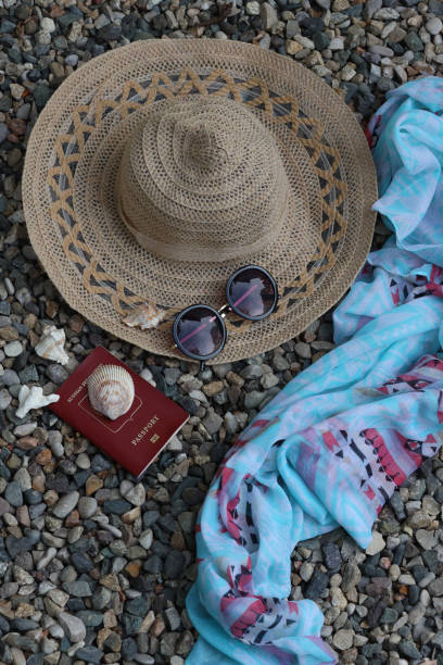 istock Hat and sunglasses on a pebble beach, passport and shawl 1325600992