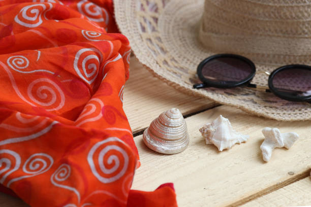 Hat and sunglasses, scarf and shells. Summer themes, vacations