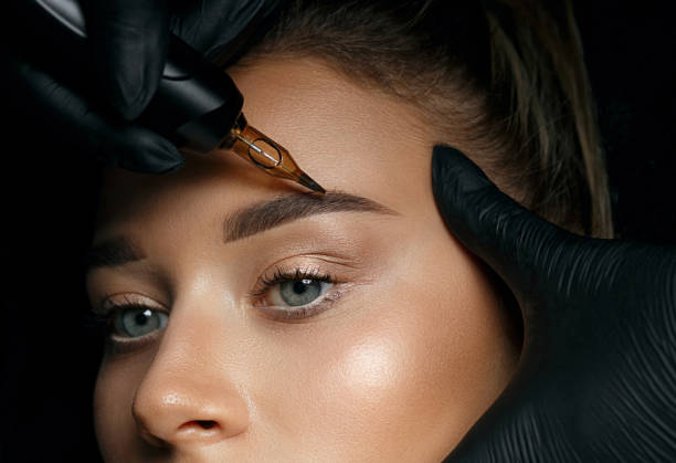 Woman in gloves applying eyebrow permanent makeup