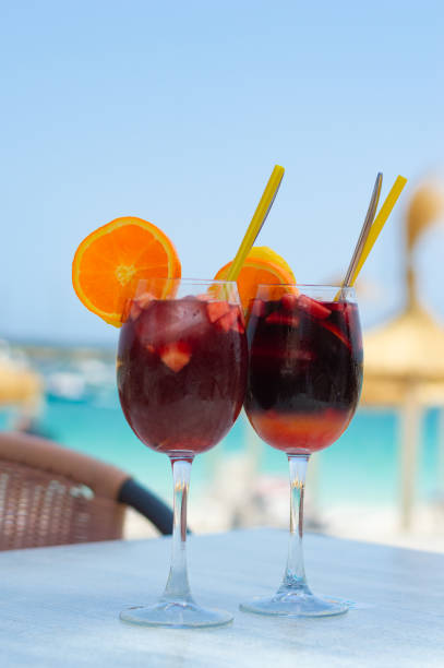 deux délicieux verres de sangria et la plage en arrière-plan défocalisé. concept d’été - beach table peach fruit photos et images de collection