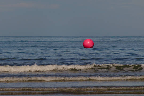 istock Pink inflatable sphere, floating before the surf on Indaia beach. 1325611458