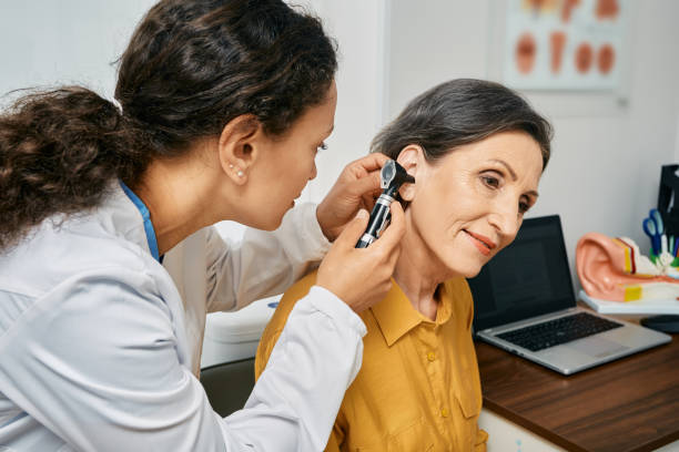 hörprüfung für ältere bürger. otolaryngologist arzt überprüft reife frau ohr mit otoscope oder auriscope in der medizinischen klinik - audiologe stock-fotos und bilder