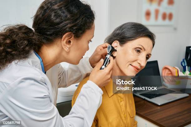 Hearing Exam For Elderly Citizen People Otolaryngologist Doctor Checking Mature Womans Ear Using Otoscope Or Auriscope At Medical Clinic Stock Photo - Download Image Now