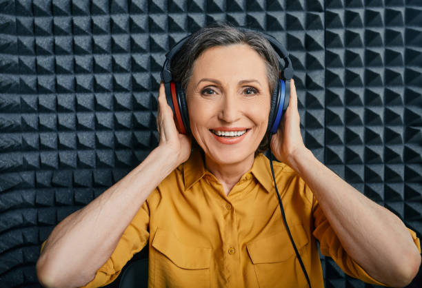 trattamento per la perdita dell'udito. donna matura positiva che indossa cuffie audiometriche durante il test dell'udito e l'audiogramma in una stanza audio speciale - esame otorino foto e immagini stock