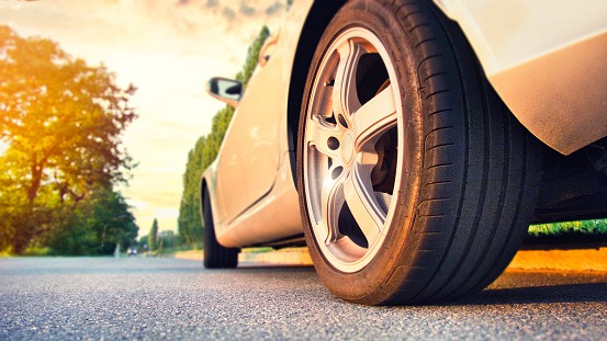Neumático de coche cerca en la carretera de asfalto al atardecer photo