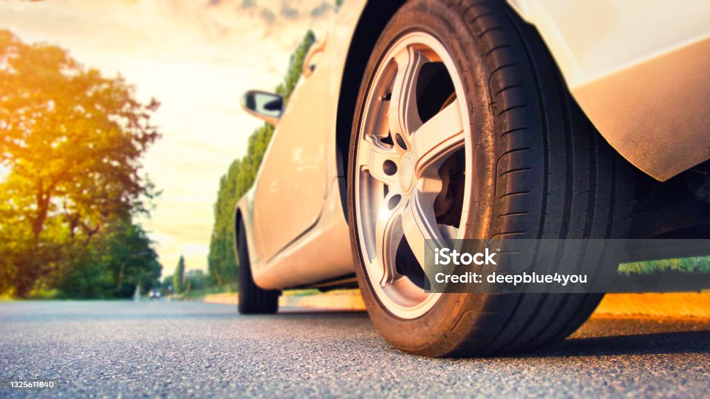Car tire close up on asphalt road at sunset Tire - Vehicle Part Stock Photo