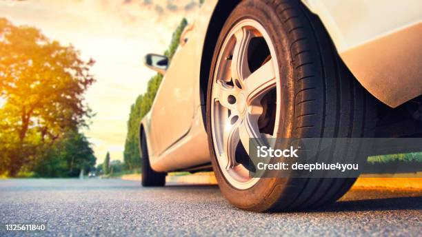 Car Tire Close Up On Asphalt Road At Sunset Stock Photo - Download Image Now - Tire - Vehicle Part, Car, Road