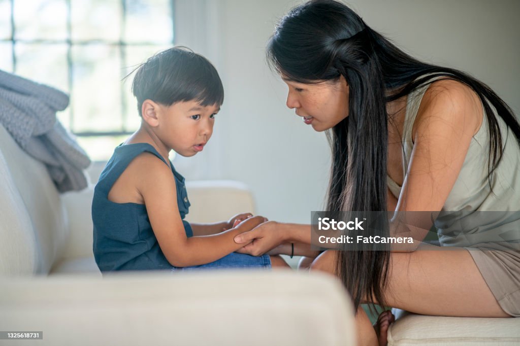 Mother teaches her son a difficult lesson A boy contemplates while his mother holds his hands and explains life to him. Child Stock Photo