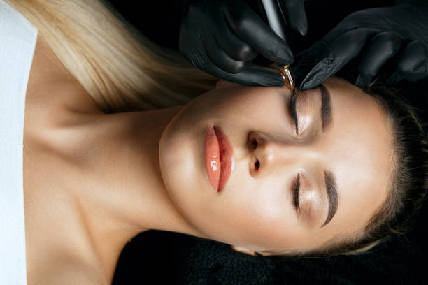 istock Tattoo artist in gloves applying permanent makeup 1325618931
