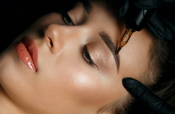 Woman in gloves applying eyebrow tattoo Top view of a beautician hand doing eyebrow permanent makeup on woman face eyebrow stock pictures, royalty-free photos & images