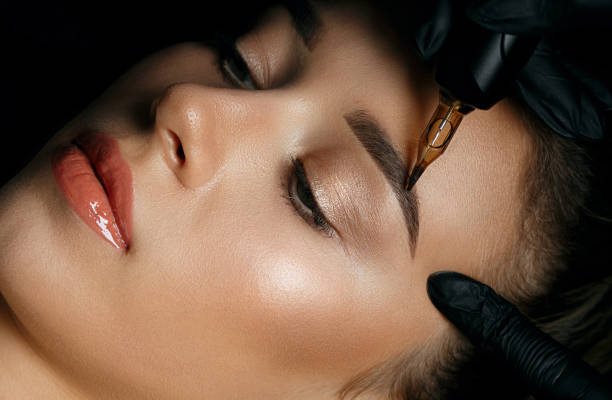 Woman in gloves applying eyebrow tattoo Top view of a beautician hand doing eyebrow permanent makeup on woman face durability stock pictures, royalty-free photos & images