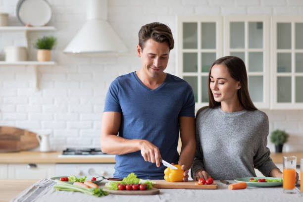 istock Beautiful young couple smiling while preparing vegetable salad in the kitchen at home. 1325619931
