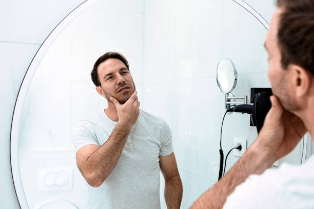 istock Reflection of man with beard looking at mirror and touching face 1325623876