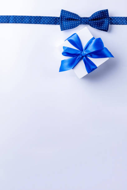 istock Father day gift. White box with bow ribbon, blue bowtie or tie on light background. Concept of Fathers Day greeting card, copy space for text. 1325633411