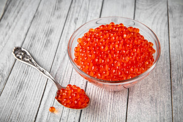 caviar rojo en un cuenco de cristal sobre un fondo blanco. producto de delicadeza - salt crystal spoon food fotografías e imágenes de stock