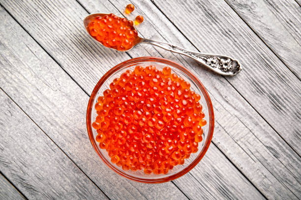 caviar rojo en un cuenco de cristal sobre un fondo blanco. producto de delicadeza - salt crystal spoon food fotografías e imágenes de stock