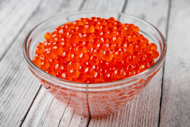 caviar rojo en un cuenco de cristal sobre un fondo blanco. producto de delicadeza - salt crystal spoon food fotografías e imágenes de stock