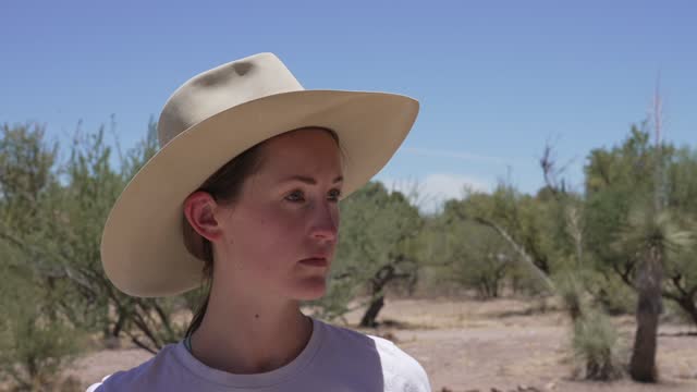 caucasian woman puts on cowboy hat in the desert