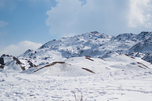 open mountain field covered by a thick layer of fresh snow on a bright daylight