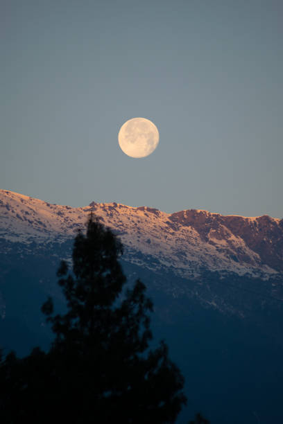 istock shining full moon visible while the first rays of the sun starts to fall on the snow covered himalayan mountain 1325667411