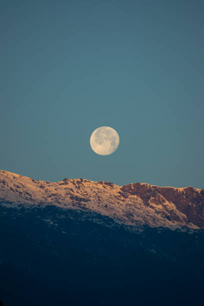 istock shining full moon visible while the first rays of the sun starts to fall on the snow covered himalayan mountain 1325667435