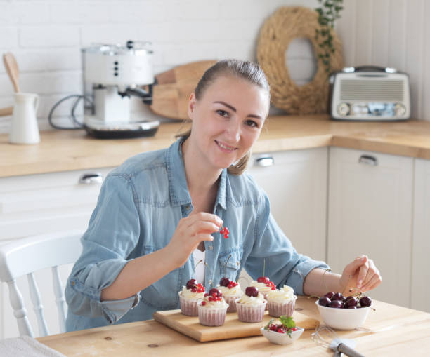 istock Young woman pastry chef decorates cupcakes with berries 1325673460