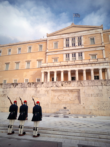Athens - Greece - 7th January 2020. Changing of the Guard at the Tomb of the Unknown Soldier in Syntagma Square, Athens performed by the Evzones (presidential guard).  The parliament building is behind with the Greek flag flying.