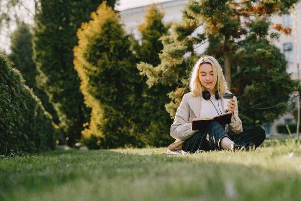 istock Blonde sitting on a grass with headphones 1325675367