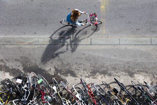 Unidentified woman riding bicycle by the bicycle parking in Bern, Switzerland. At 2015 15% of Bern inhabitants were traveling by bicycle.