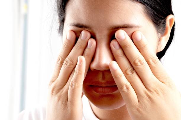 Overwork, stress. Asian businesswoman holding glasses feels pain, dry eyes or headache suffers from blurry poor vision. stock photo