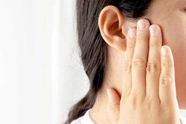 Young woman suffering from earache and tinnitus Causes of ear pain include otitis media and earwax buildup. stock photo