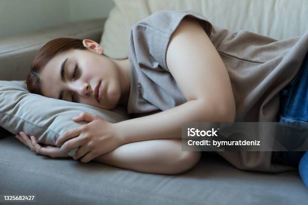 Young Woman Sleeping On Her Living Room Sofa Stock Photo - Download Image Now - Sleeping, Teenage Girls, Sofa