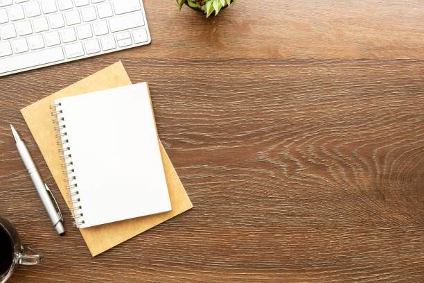 istock Blank notebook with pen are on top of wood office desk table with computer tools, cup of coffee and supplies. Top view with copy space, flat lay. 1325685068