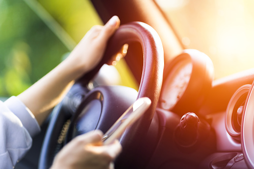 Shot of a woman using cell phone while driving a car