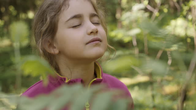 Portrait Child Girl Exhaling Fresh Air, Taking Deep Breath, Reducing Stress in Forest. Dreamy peaceful relaxed smiling kid girl breathing fresh air nature, tranquil caucasian child alone outdoors.
