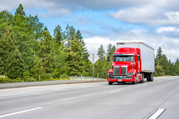 istock Bright red compact powerful big rig semi truck transporting cargo in dry van semi trailer moving on the wide highway road 1325695494