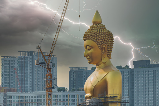 Gigantic Buddha statue under construction with lightning streak in background