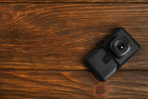 istock Modern car dashboard camera on wooden background, top view. Space for text 1325698810