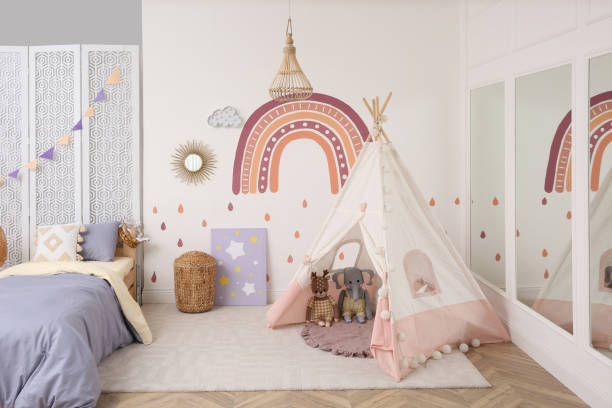 istock Stylish room with comfortable bed and teepee tent for kids. Interior design 1325699791
