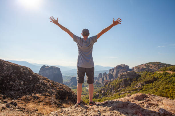 istock Happy man traveller standing with hands up in mountain 1325700639