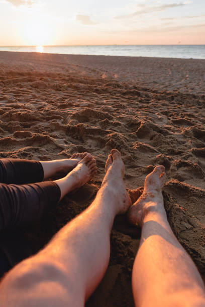 istock couple sitting on sandy beach looking on sunset 1325700995