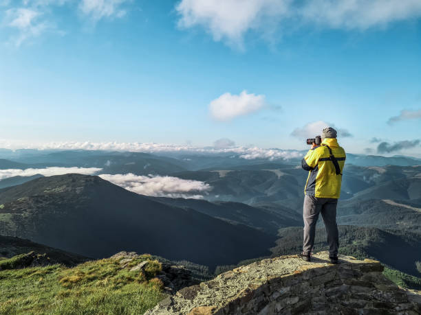 istock hiker man with camera taking picture of mountains 1325701054