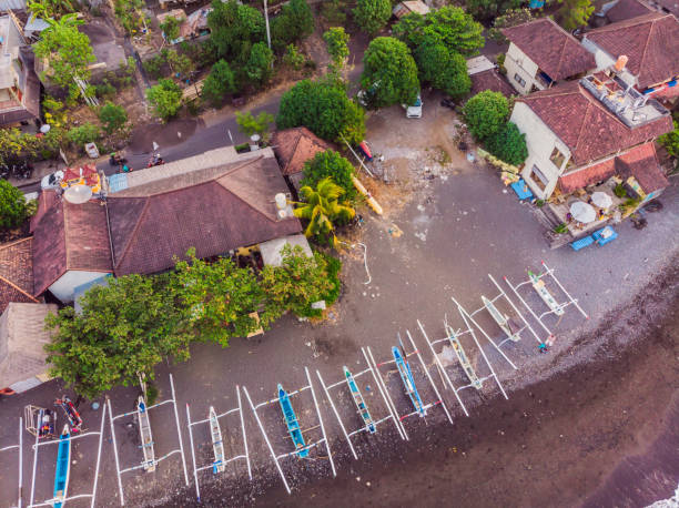 vista aérea de la playa de amed en bali, indonesia. barcos de pesca tradicionales llamados jukung en la playa de arena negra y el volcán monte agung en el fondo, parcialmente cubierto por nubes - jukung fotografías e imágenes de stock