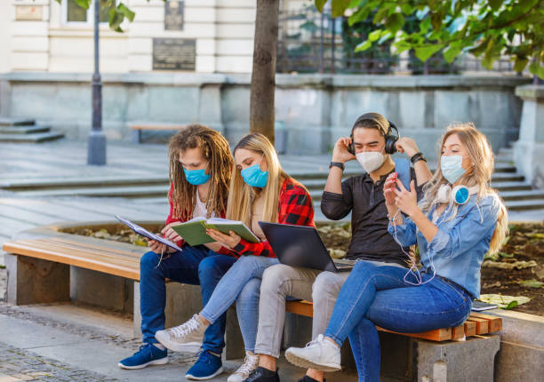 istock Beautiful Students are Working on a Laptop in Public Park with Preventive Measures due to Coronavirus. 1325704189