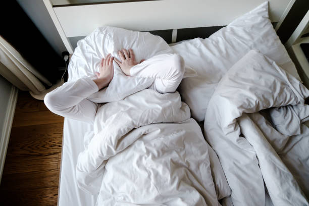 istock Man cannot fall asleep due to noise, he is tired and in stress covers head with a pillow. Insomnia concept. 1325708694