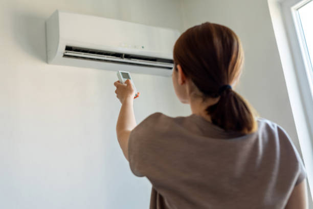 femme allume le climatiseur avec télécommande - climatiseur photos et images de collection